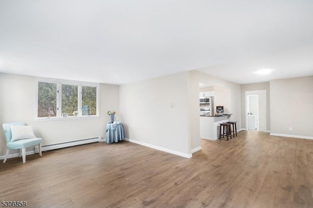 unfurnished room featuring light wood-type flooring and a baseboard heating unit