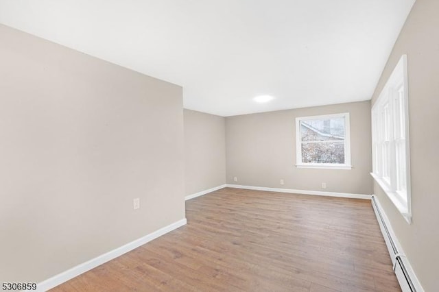 unfurnished room with a baseboard heating unit and light wood-type flooring