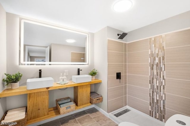 bathroom featuring a tile shower, vanity, and toilet