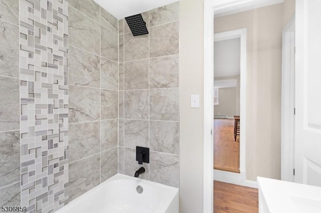 bathroom with wood-type flooring, tiled shower / bath combo, and a baseboard radiator