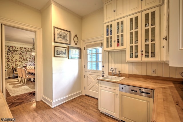 kitchen featuring crown molding, white cabinetry, sink, and dishwashing machine