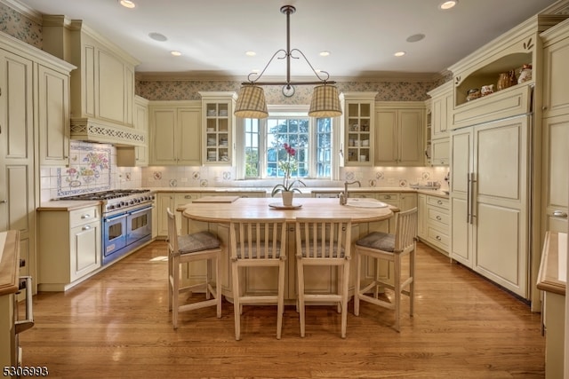 kitchen with a center island with sink, cream cabinetry, a kitchen breakfast bar, and double oven range