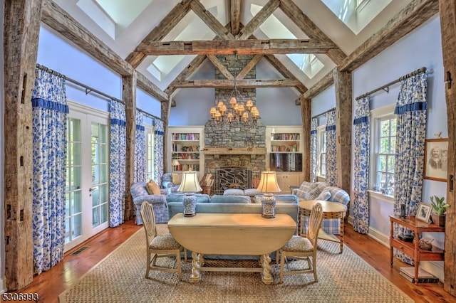 dining room with a stone fireplace, hardwood / wood-style floors, and high vaulted ceiling