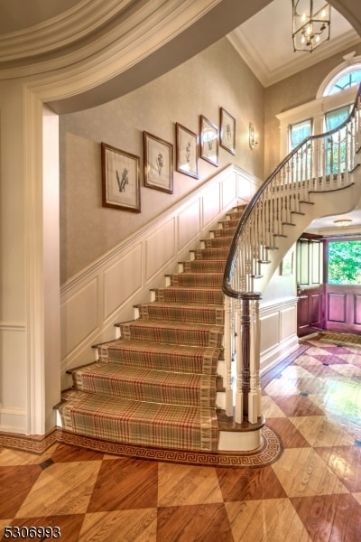 stairway featuring an inviting chandelier and crown molding