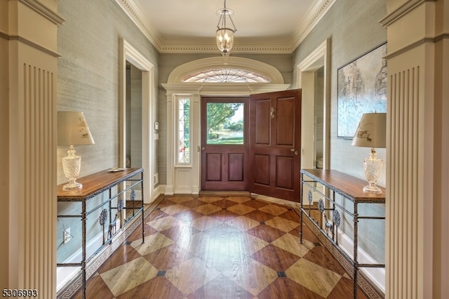 foyer with crown molding and an inviting chandelier