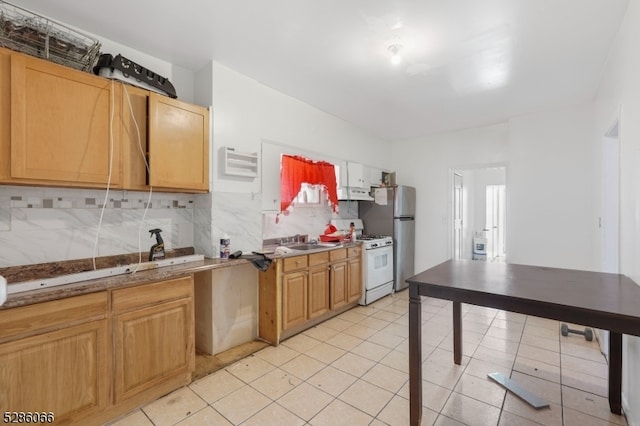 kitchen featuring sink, decorative backsplash, light tile patterned floors, refrigerator, and white range with gas cooktop