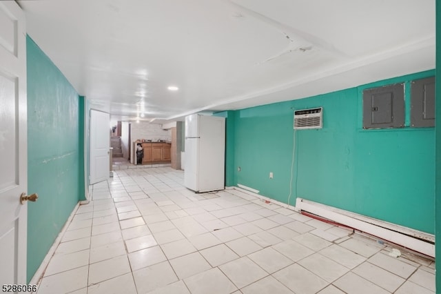 basement featuring a wall mounted AC, white fridge, a baseboard heating unit, and light tile patterned floors