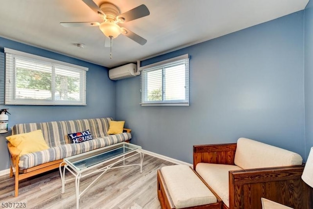 living area featuring ceiling fan, a wall unit AC, wood finished floors, and baseboards