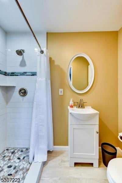 bathroom featuring baseboards, toilet, vanity, and a shower stall