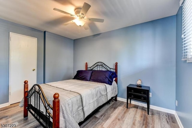 bedroom featuring a ceiling fan, baseboards, and wood finished floors