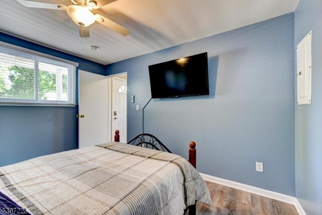 bedroom with electric panel, ceiling fan, and hardwood / wood-style flooring