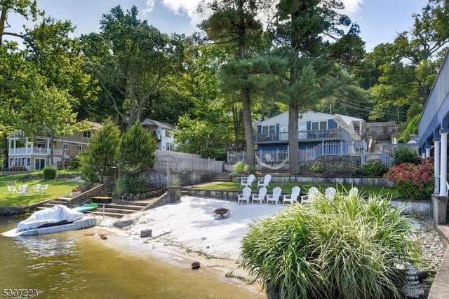 view of property's community with an outdoor fire pit, a water view, and fence