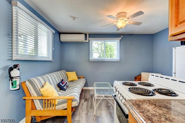 kitchen featuring white appliances, a wall unit AC, hardwood / wood-style flooring, and ceiling fan