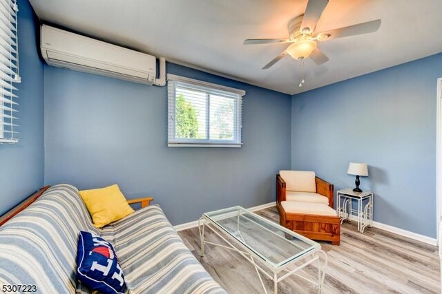 sitting room featuring ceiling fan, a wall unit AC, and wood-type flooring