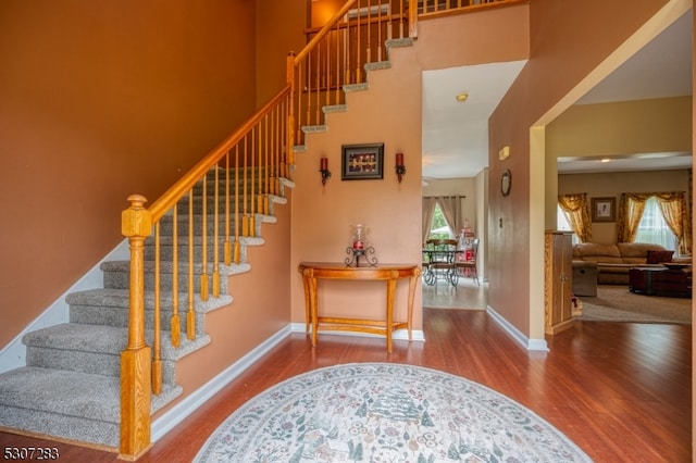 stairway featuring hardwood / wood-style flooring and a towering ceiling