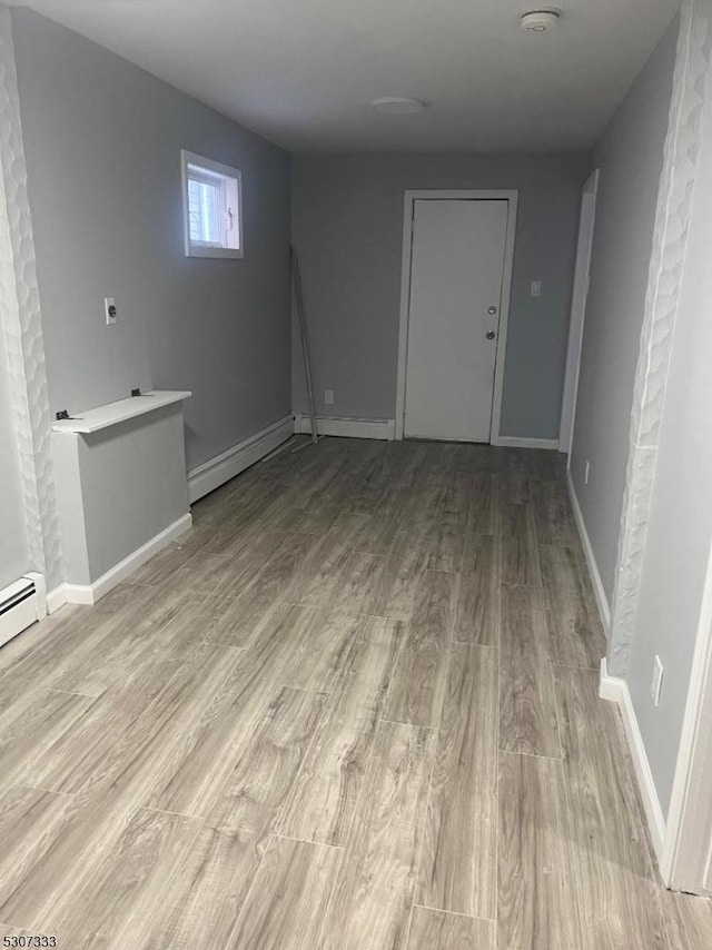 interior space featuring baseboard heating and light hardwood / wood-style floors