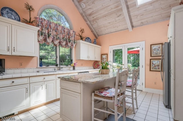 kitchen with stainless steel refrigerator, light tile patterned flooring, plenty of natural light, and a kitchen island