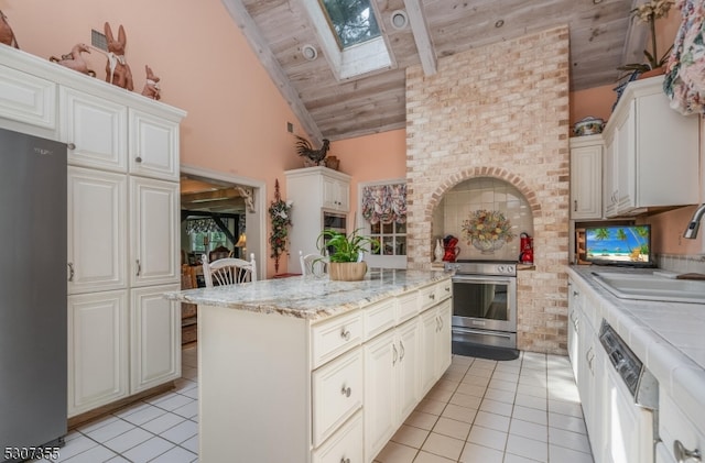 kitchen featuring high vaulted ceiling, wooden ceiling, black refrigerator, a skylight, and stainless steel range