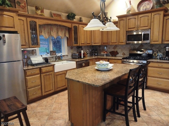 kitchen featuring stainless steel appliances, backsplash, a breakfast bar, a center island, and decorative light fixtures