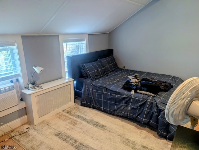 bedroom with multiple windows, hardwood / wood-style floors, and vaulted ceiling