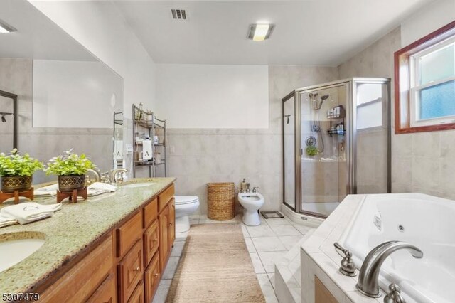 full bathroom featuring toilet, tile patterned flooring, vanity, tile walls, and a bidet