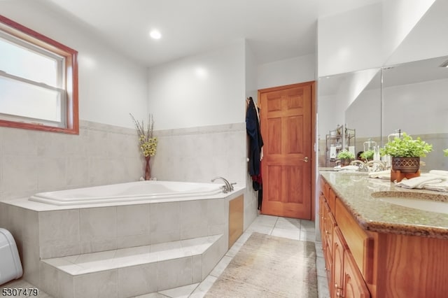 bathroom featuring tile patterned flooring, vanity, and tiled bath