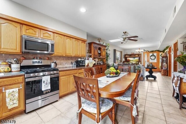 kitchen with ceiling fan, stainless steel appliances, light tile patterned flooring, and decorative backsplash