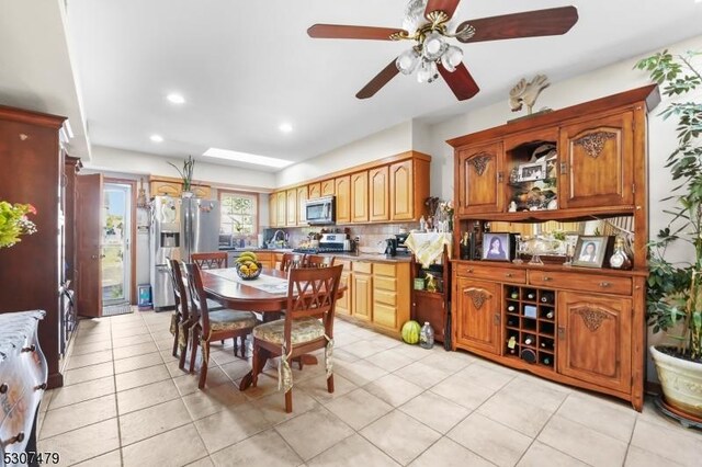 kitchen featuring ceiling fan, backsplash, light tile patterned floors, and stainless steel appliances