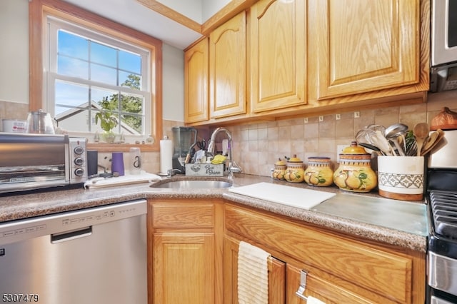 kitchen with stainless steel dishwasher, sink, backsplash, and light brown cabinetry