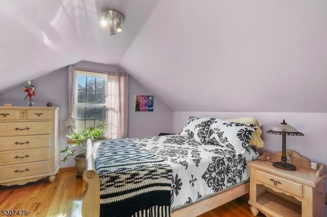 bedroom featuring light hardwood / wood-style floors and lofted ceiling