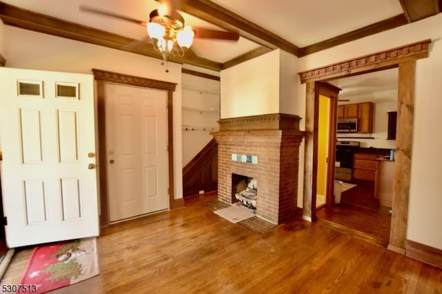 living room featuring crown molding, ceiling fan, hardwood / wood-style floors, and a fireplace