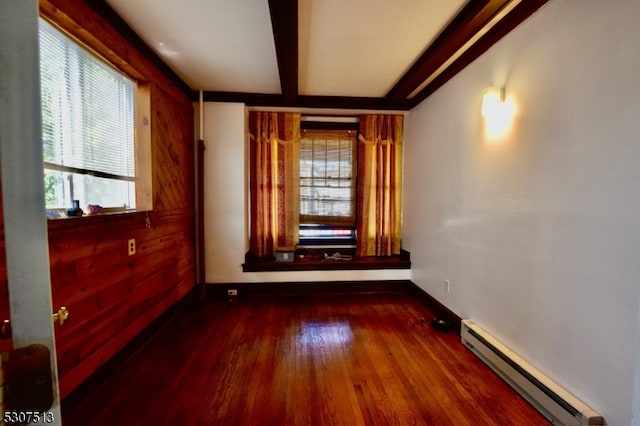 unfurnished room with a baseboard radiator, wooden walls, and dark hardwood / wood-style floors