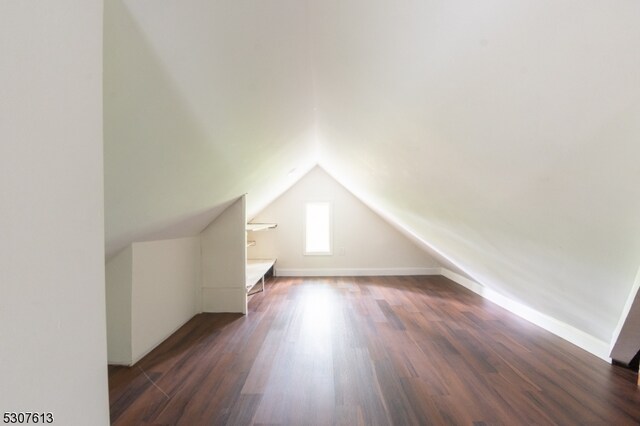 additional living space featuring vaulted ceiling and dark hardwood / wood-style floors