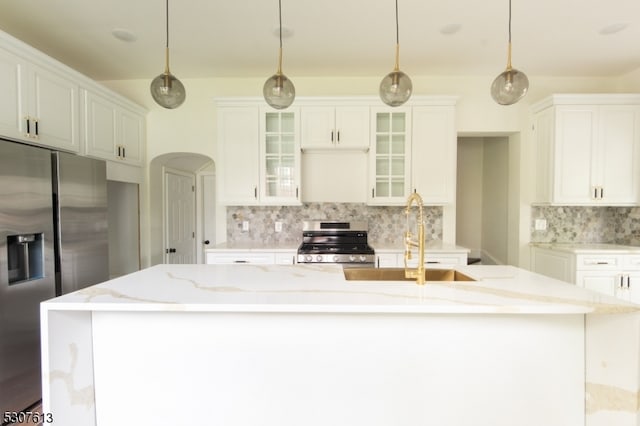 kitchen featuring white cabinets, a center island with sink, appliances with stainless steel finishes, pendant lighting, and sink