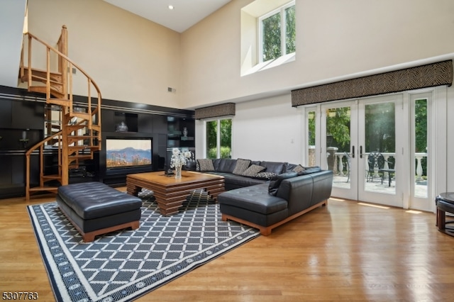 living room featuring a wealth of natural light, light hardwood / wood-style flooring, a high ceiling, and french doors