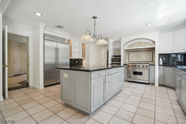 kitchen with light tile patterned floors, tasteful backsplash, high end appliances, and a kitchen island