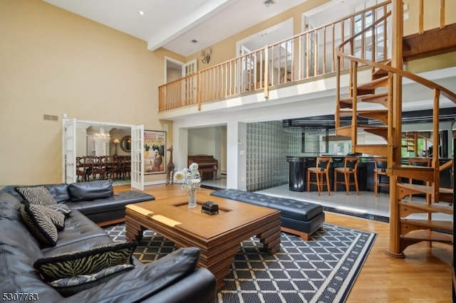 living room featuring beamed ceiling, hardwood / wood-style flooring, and a towering ceiling