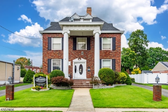 neoclassical home featuring a front yard