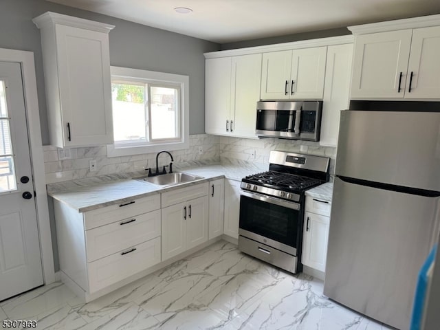 kitchen featuring appliances with stainless steel finishes, white cabinetry, tasteful backsplash, sink, and light tile patterned floors