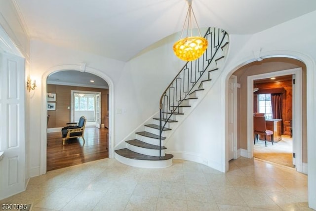 entrance foyer featuring arched walkways, a healthy amount of sunlight, and stairs