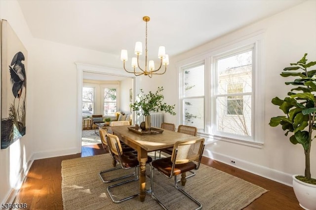 dining room with dark wood-type flooring, radiator, and an inviting chandelier