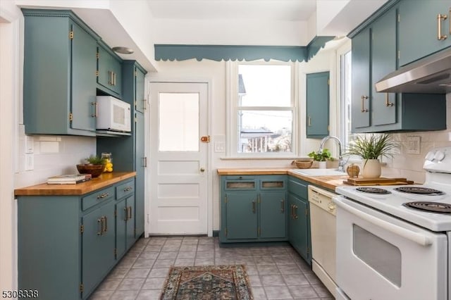 kitchen featuring sink, light tile patterned floors, white appliances, and decorative backsplash