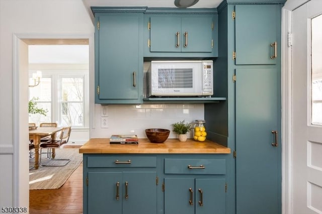 kitchen with dark hardwood / wood-style flooring, decorative backsplash, butcher block counters, and blue cabinets