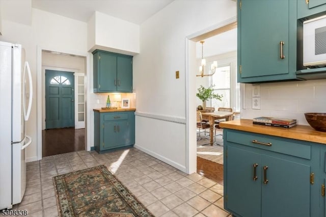 kitchen featuring light tile patterned flooring, butcher block countertops, tasteful backsplash, a notable chandelier, and white appliances