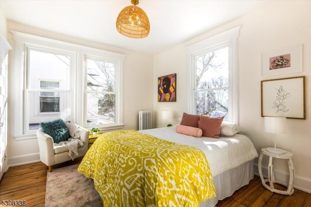 bedroom featuring multiple windows, radiator, and dark hardwood / wood-style flooring