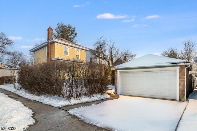 view of snowy exterior with a garage and an outdoor structure