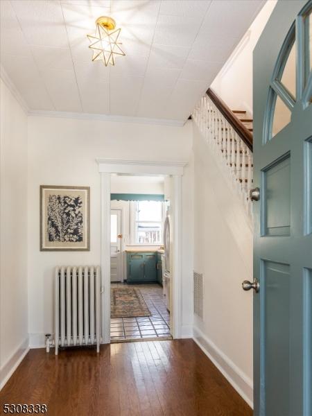 corridor with crown molding, radiator heating unit, and dark hardwood / wood-style flooring