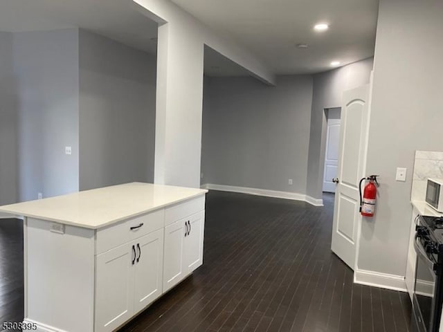 kitchen featuring white cabinetry, black gas stove, baseboards, light countertops, and dark wood finished floors