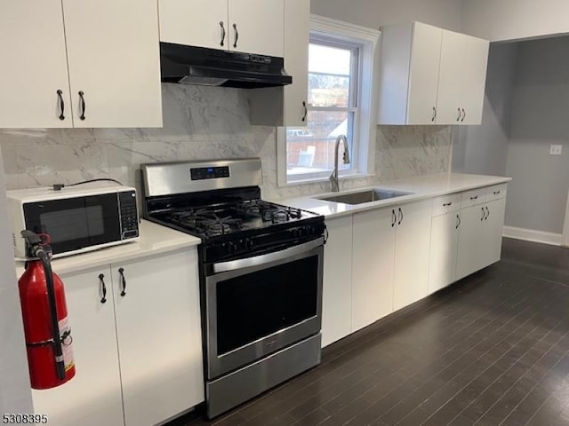 kitchen featuring black microwave, under cabinet range hood, a sink, light countertops, and stainless steel gas stove