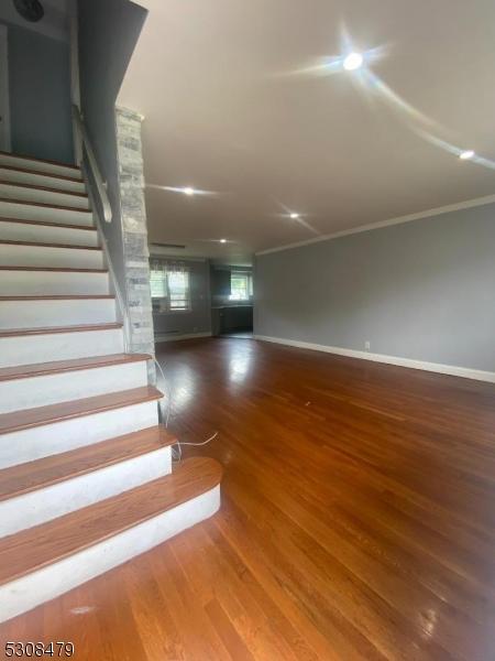 stairs with ornamental molding, wood finished floors, and baseboards